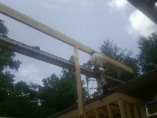 Carpenter setting a ridge beam over a new addition frame — Ice Dam Removal by Roofing Brothers in Canton