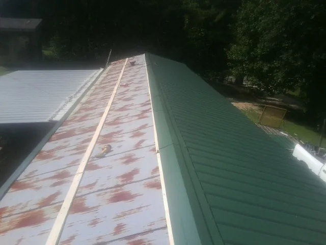 Old rusted panels beside newly installed green metal roofing — Wind Damage Roof Repair by Roofing Brothers in Canton